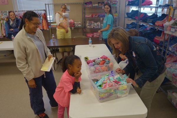 5 - Volunteers help a little girl pick out new clothes